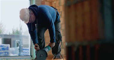 Betonu kesmek için elektrikli alet kullanan işçiler, üçkağıtçıdan uçan kıvılcımlar, kullanımda olan güvenlik teçhizatı, inşaat sürecine yakın çekim, hassasiyet ve işçiliğe adanmışlık