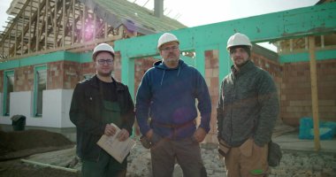 İnşaat işçileri inşaat sahasında birlikte duruyorlar. İnşaat projesi, birlik ve inşaat sektöründe çalışan profesyonellerden oluşan bir ekip.