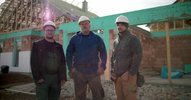 İnşaat alanında çalışan bir grup inşaat işçisi, birlik içinde duruyorlar, inşaat alanında işbirliği yapan inşaat profesyonelleri, takım çalışması ve koordinasyon