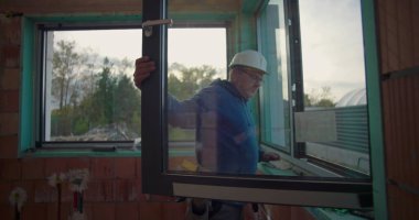 İnşaat alanındaki pencere çerçevesini ayarlayan işçiler, konut inşaatı projesinde doğru kurulum olup olmadığını kontrol ediyorlar, kalite kontrol odağı