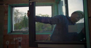 İnşaat alanındaki pencere çerçevesini ayarlayan işçiler, konut inşaatı projesinde doğru kurulum olup olmadığını kontrol ediyorlar, kalite kontrol odağı