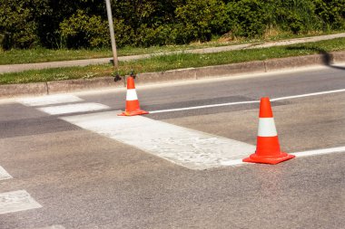 Yol üzerinde çalışması. İnşaat külah. Trafik koni, asfalt üzerinde beyaz ve turuncu çizgili. Sinyal için ev ve trafik işaretleri. İnşaat işareti ve trafik konileri yolda altında yol bakım.