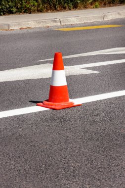 Yolda çalış. İnşaat konisi. Asfalt üzerinde beyaz ve turuncu çizgileri olan trafik konisi. İşaret için sokak ve trafik işaretleri. Yol bakımı, yol tabelası ve trafik konisi altında..