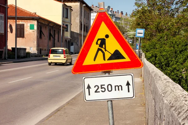 Road works sign for construction works in city street. Road under construction traffic sign. Traffic, warning sign road repairing. Outdoor street sign. Red, black and yellow triangle road sign work.