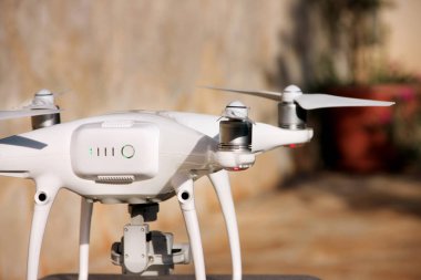 Beyaz quadcopter dron stand 4 k dijital kamera ile fotoğraf çekmek, görüntüleri yukarıdan kayıt için havada uçmaya kalkış için hazır. Dört motorlar, pervaneleri, kamera ve kırmızı uyarı lambaları ile robot.