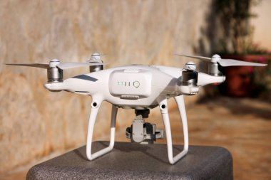 Beyaz quadcopter dron stand 4 k dijital kamera ile fotoğraf çekmek, görüntüleri yukarıdan kayıt için havada uçmaya kalkış için hazır. Dört motorlar, pervaneleri, kamera ve kırmızı uyarı lambaları ile robot.