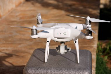 Beyaz quadcopter dron stand 4 k dijital kamera ile fotoğraf çekmek, görüntüleri yukarıdan kayıt için havada uçmaya kalkış için hazır. Dört motorlar, pervaneleri, kamera ve kırmızı uyarı lambaları ile robot.