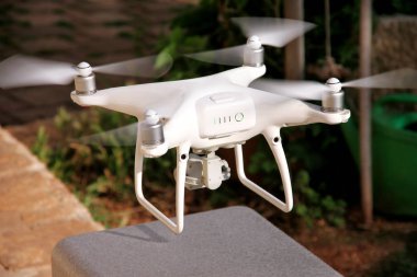 Beyaz dört helikopter Drone ile 4 k dijital fotoğraf makinesi almak için ve kapalı 's havada, fotoğraf çekmek ve yukarıdan görüntüleri kaydetmek için yüksek sinek. Dört motorlar, pervaneleri, kamera ve kırmızı uyarı lambaları ile robot.