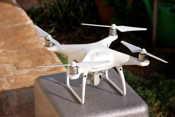 Beyaz quadcopter dron stand 4 k dijital kamera ile fotoğraf çekmek, görüntüleri yukarıdan kayıt için havada uçmaya kalkış için hazır. Dört motorlar, pervaneleri, kamera ve kırmızı uyarı lambaları ile robot.