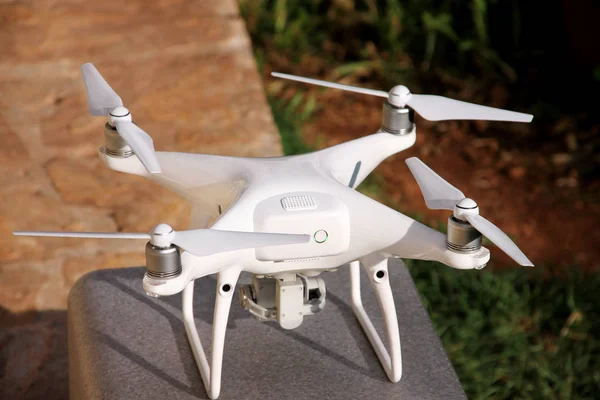 Beyaz quadcopter dron stand 4 k dijital kamera ile fotoğraf çekmek, görüntüleri yukarıdan kayıt için havada uçmaya kalkış için hazır. Dört motorlar, pervaneleri, kamera ve kırmızı uyarı lambaları ile robot.