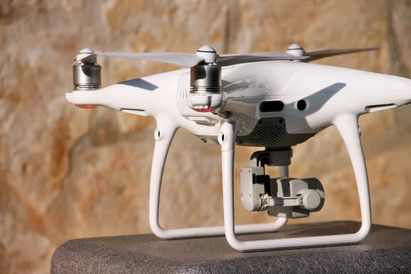 Beyaz quadcopter dron stand 4 k dijital kamera ile fotoğraf çekmek, görüntüleri yukarıdan kayıt için havada uçmaya kalkış için hazır. Dört motorlar, pervaneleri, kamera ve kırmızı uyarı lambaları ile robot.