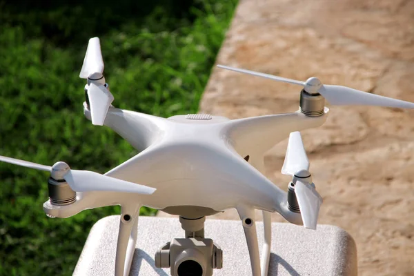 Beyaz quadcopter dron stand 4 k dijital kamera ile fotoğraf çekmek, görüntüleri yukarıdan kayıt için havada uçmaya kalkış için hazır. Dört motorlar, pervaneleri, kamera ve kırmızı uyarı lambaları ile robot.