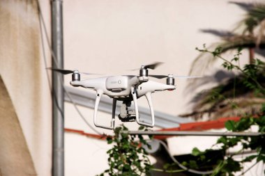 Modern beyaz dört helikopter ile 4 k dijital kamera fotoğraf çekmek ve yukarıdan görüntüleri kaydetmek için havadaki uçan robot. Dört motorlar, pervaneleri, kamera ve kırmızı uyarı lambaları ile robot. Teknoloji.