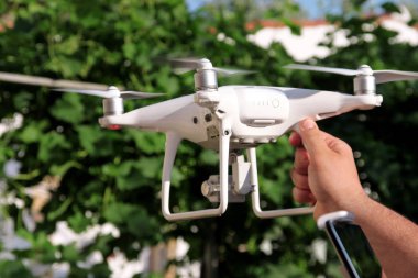 Adam elinde bir dron holding ve yeni teknoloji kullanarak. Beyaz dört helikopter uçak ve fotoğrafçı adam ellerini. Uzaktan kontrol paneli ekran ve kontrolleri ile profesyonel casus uçak pilot tutar.