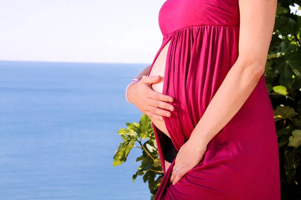 美丽的孕妇和夫人拥抱和抱着她怀孕的肚子 站在自然环境中 等待婴儿 妈妈在海上和天空的自然背景下手 — 图库照片
