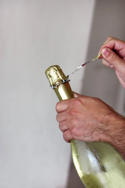 Man is opening a bottle of champagne. Waiter opens a bottle of wine. Man hands open bottle of champagne alcohol and wine drink on party celebration event. Hands close up. Celebration and holidays.