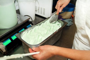 Pudra Şef üniforma içinde dondurma fabrikasında çalışıyor. Süslemeleri İtalyan krem nane dondurma tatlar çelik kap içinde bir kadındır. Üretim, sanayi, üretim, insanlar kavramı.