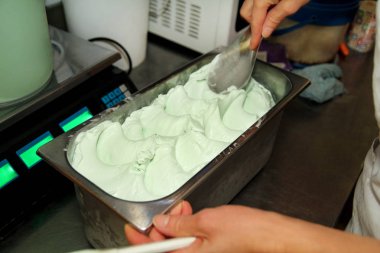 Pudra Şef üniforma içinde dondurma fabrikasında çalışıyor. Süslemeleri İtalyan krem nane dondurma tatlar çelik kap içinde bir kadındır. Üretim, sanayi, üretim, insanlar kavramı.