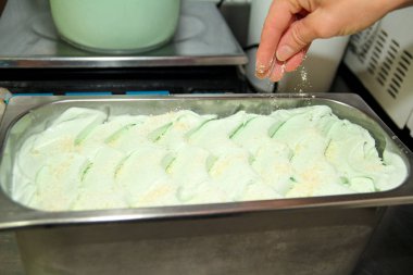 Pudra Şef üniforma içinde dondurma fabrikasında çalışıyor. Süslemeleri İtalyan krem nane dondurma tatlar çelik kap içinde bir kadındır. Üretim, sanayi, üretim, insanlar kavramı.