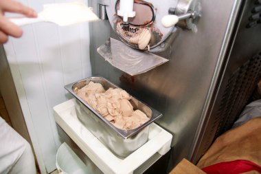Pudra Şef üniforma içinde Ice cream maker makina üzerinde çalışıyor. Kadın fındık aromalı dondurma üreten, çelik kap içine düşüyor. İtalyan kremalı dondurma endüstriyel hazırlanması.