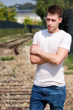 Yakışıklı genç bir adam poz ve güzel bir güneşli gün zevk güneş gözlüklü. Kentsel şehir ortamı. Eski Tren içinde geçmiş. Erkek model fotoğraf çekimi, kentsel moda, yaşam tarzı. Beyaz T-shirt ve jeans.