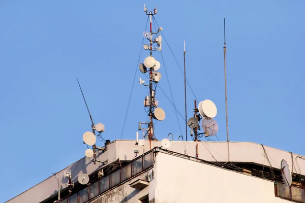 Telecommunication base stations network repeaters on the roof of building. The cellular communication aerial on city building roof. Cell phone telecommunication tower. Antennas on top of building.