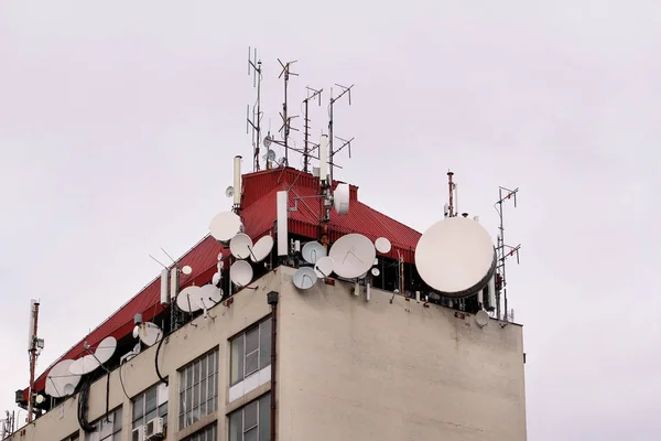 Telecommunication base stations network repeaters on the roof of building. The cellular communication aerial on city building roof. Cell phone telecommunication tower. Antennas on top of building.