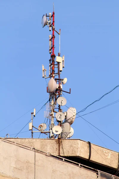 Telecommunication base stations network repeaters on the roof of building. The cellular communication aerial on city building roof. Cell phone telecommunication tower. Antennas on top of building.