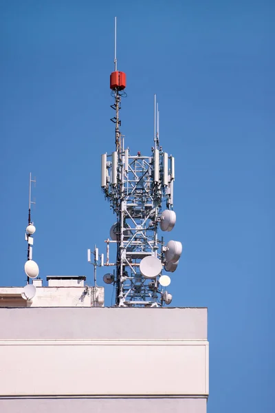 Telecommunication base stations network repeaters on the roof of building. The cellular communication aerial on city building roof. Cell phone telecommunication tower. Antennas on top of building.