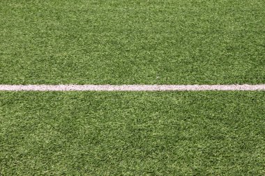 Part of sport soccer stadium and artificial turf football field. Detail, close up of green grass with white lines, goal line, corner line. Focus football field selected background, texture, wallpaper.