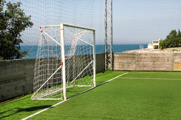 Soccer goal door with white net. Football goal at soccer field with green grass and sport stadium on campus, bleachers, white line and soccer field corner. Sports elements, equipment and environment.