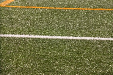 Part of sport soccer stadium and artificial turf football field. Detail, close up of green grass with white lines, goal line, corner line. Focus football field selected background, texture, wallpaper.