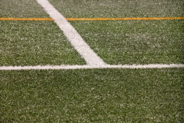 Part of sport soccer stadium and artificial turf football field. Detail, close up of green grass with white lines, goal line, corner line. Focus football field selected background, texture, wallpaper.