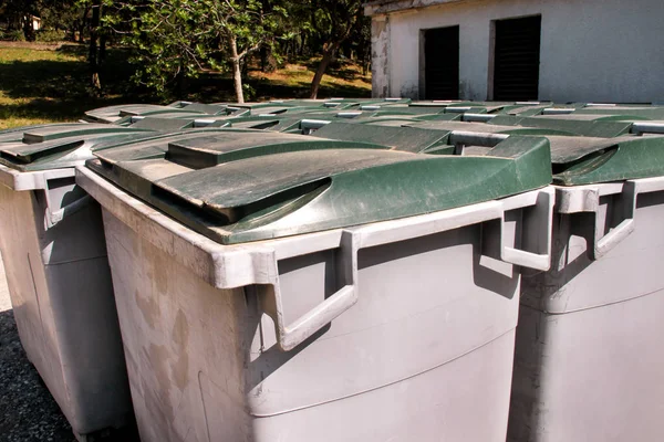 Large garbage containers, trash dumpsters and bins standing in row. Orderly stowed garbage cans ready for separate garbage collection. Environmentally friendly trash containers, recycle bins, tanks.