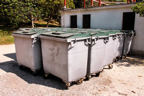 Large garbage containers, trash dumpsters and bins standing in row. Orderly stowed garbage cans ready for separate garbage collection. Environmentally friendly trash containers, recycle bins, tanks.