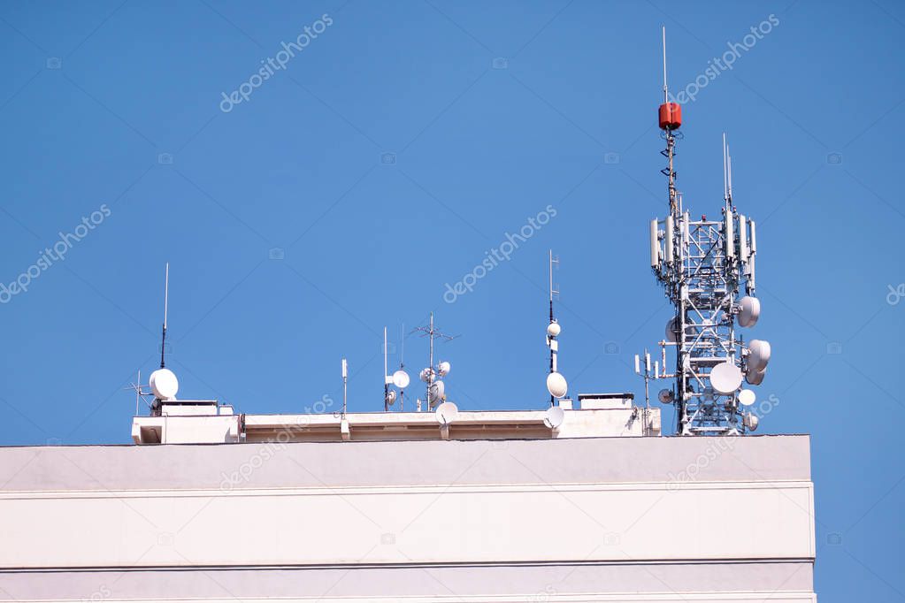 Telecommunication base stations network repeaters on the roof of building. The cellular communication aerial on city building roof. Cell phone telecommunication tower. Antennas on top of building.