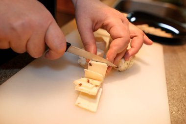 Kadın el parça peynir kesme, o mutfak yemek hazırlamak. Şef kesme peynir restoran mutfak masasının üzerinde ahşap tahta üzerinde bıçakla. Ev hanımı bir bıçakla dilimlenmiş peynir kesme tahtası üzerinde.