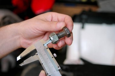 İşçi elinde araçlarıyla. Mekanik kontrol ve vida boyutu paslanmaz çelik gövde automechanics atölye, araç garaj ile ölçme. Çelik gövde kullanarak eller mekanik holding çelik vida.