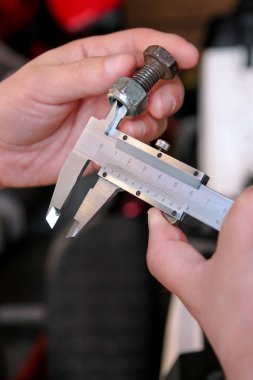 İşçi elinde araçlarıyla. Mekanik kontrol ve vida boyutu paslanmaz çelik gövde automechanics atölye, araç garaj ile ölçme. Çelik gövde kullanarak eller mekanik holding çelik vida.