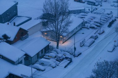 Otopark ve sokak arabalar büyük kar tabakası ile kaplı. Kış ve kar taneleri ile caddenin üzerinde kar yağışı görünümünü. Kış günü sürüklenen kar nedeniyle motorlu araçlar ile çok karlı mevsimde kar.
