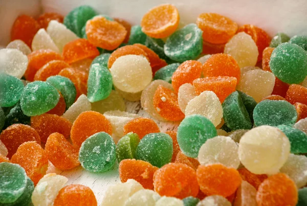 Different gelatin sweet fruit candy candies sugar. Assorted colorful jelly sweets. Colored confectionery for kids. Delicious multicolor candies in box. White, green, orange, yellow color background.
