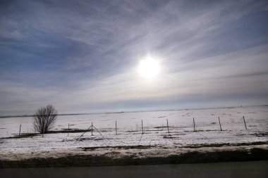 Karayolu kış manzara çayırlar ve kar tabakası ile kaplı alanlar üzerinden görüntüleyin. Mavi gökyüzü ve güneş ile inanılmaz doğal çevre. Kışın mevsim belirli karla kaplı güzel manzara.