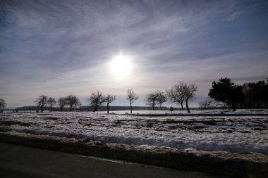 Karayolu kış manzara çayırlar ve kar tabakası ile kaplı alanlar üzerinden görüntüleyin. Mavi gökyüzü ve güneş ile inanılmaz doğal çevre. Kışın mevsim belirli karla kaplı güzel manzara.