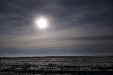 Karayolu kış manzara çayırlar ve kar tabakası ile kaplı alanlar üzerinden görüntüleyin. Mavi gökyüzü ve güneş ile inanılmaz doğal çevre. Kışın mevsim belirli karla kaplı güzel manzara.