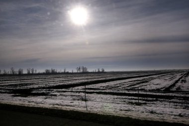 Karayolu kış manzara çayırlar ve kar tabakası ile kaplı alanlar üzerinden görüntüleyin. Mavi gökyüzü ve güneş ile inanılmaz doğal çevre. Kışın mevsim belirli karla kaplı güzel manzara.
