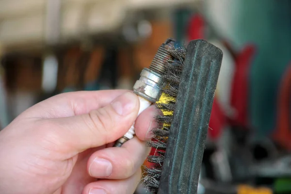 Bir araba motor buji araba garajda tel fırça ile temizliyor. Makinist kullanılan buji otomatik mekanik atölye bir paslanmaz çelik fırçayla fırçalıyor. İşçi Servisi el araçları.