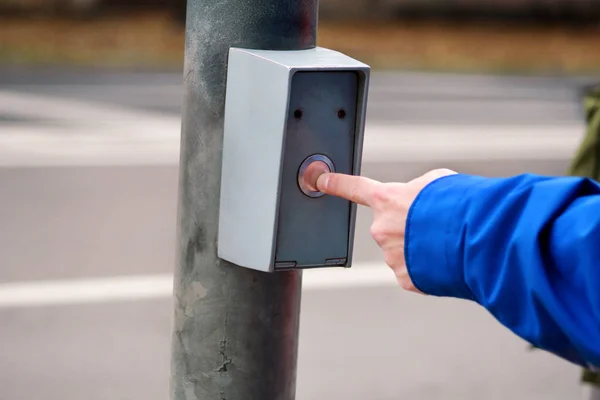 Portrait of male hand pressing button for crossing street on crosswalk and traffic light. Man standing on traffic light and pedestrian crossing, his finger is pressure on button for green light. — Stock Photo, Image