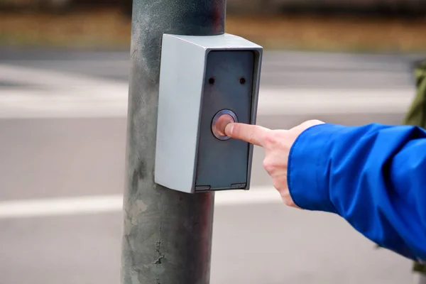 Portret van mannenhand kruising straat op zebrapad en stoplicht knop ingedrukt te houden. Mens is staande op verkeerslicht en voetgangersoversteekplaats, zijn vinger druk op de knop voor groen licht. — Stockfoto