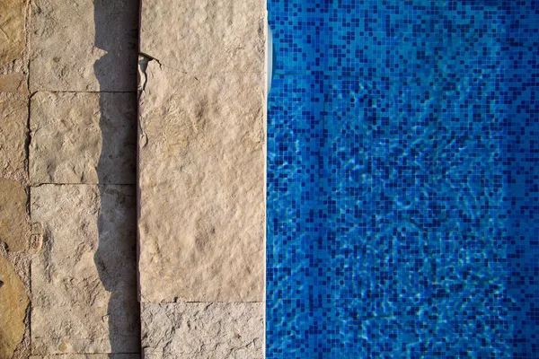 Блакитна витягнута вода в басейні в тропічному курорті з краєм тротуару. Частина нижнього фону басейну. Прозора світло-блакитна вода в басейні стискається з відбиттям сонця. Поверхня басейну . — стокове фото