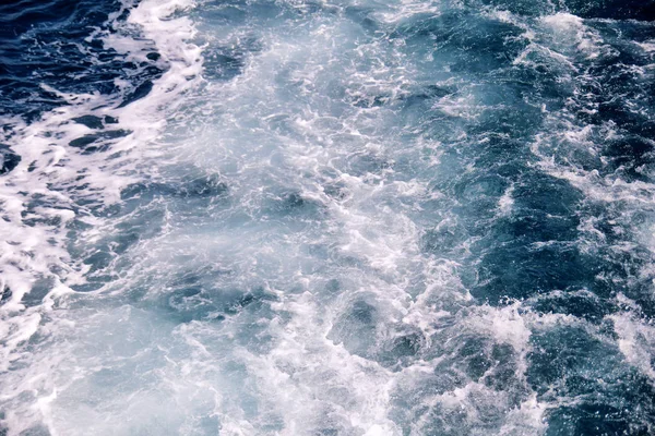 Turbulentie gemaakt door schuim van het zeewater van een snelle jacht op de oppervlakte van de zee. Blauwe zee golven met veel schuim van de zee. Oppervlakte van zee met golven, splash, schuim en bubbels, blauwe achtergrond en behang. — Stockfoto